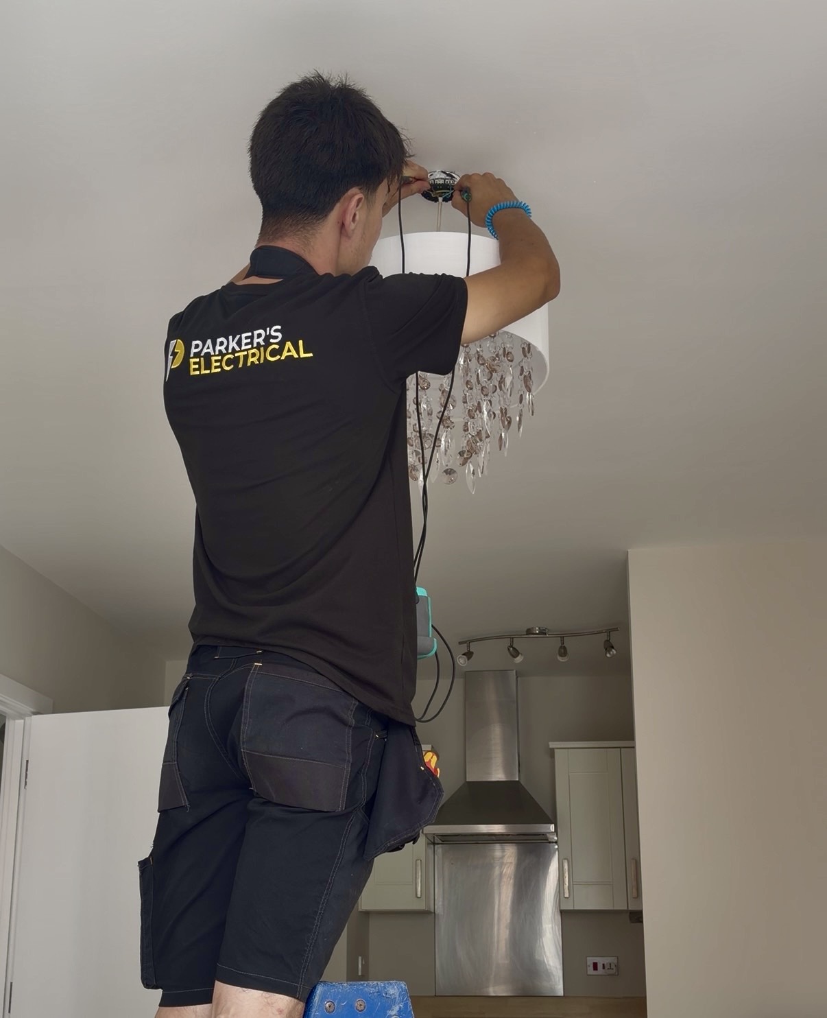 Parker's Electrical electrician inspecting and refitting a ceiling light during testing