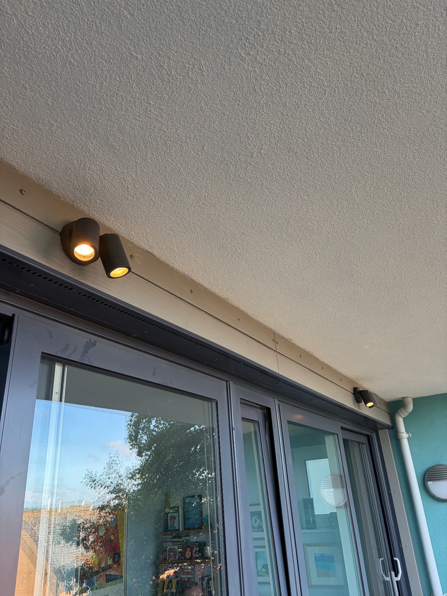 External soffit spotlights installed above sliding patio doors, lit at dusk