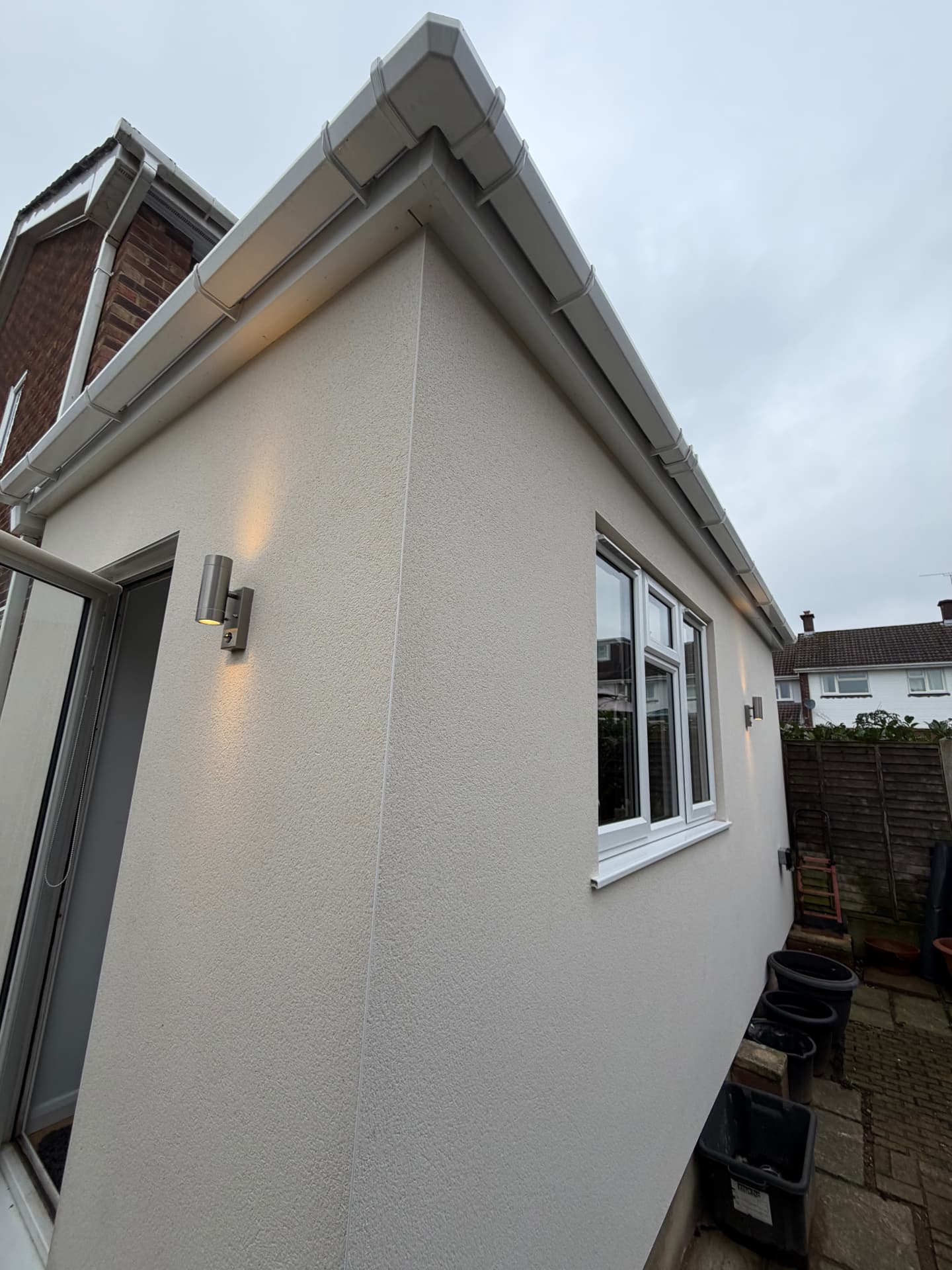 External up and down wall lights installed on a rendered garden room