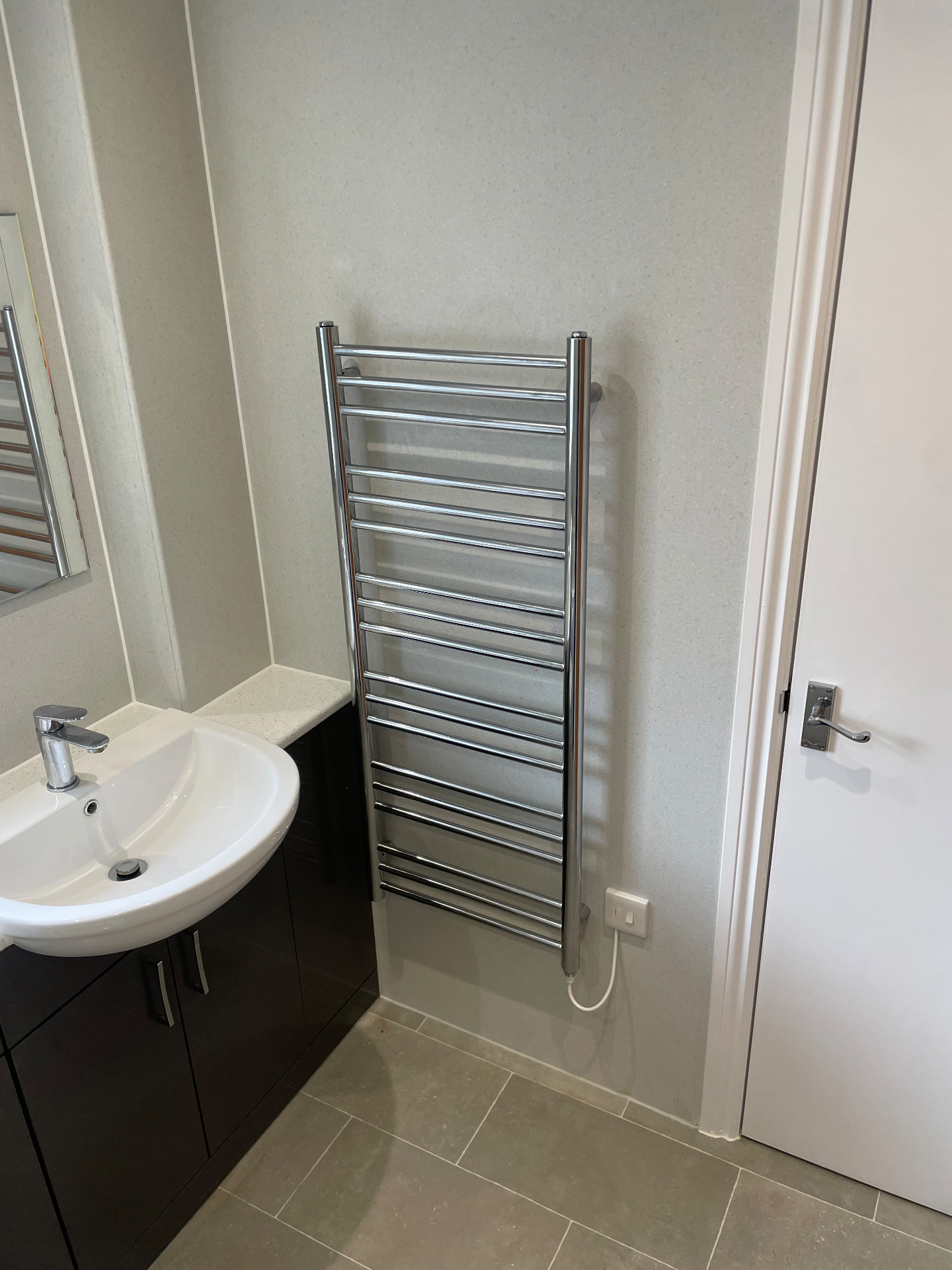 Chrome heated towel rail wired to a switched fused supply in a bathroom