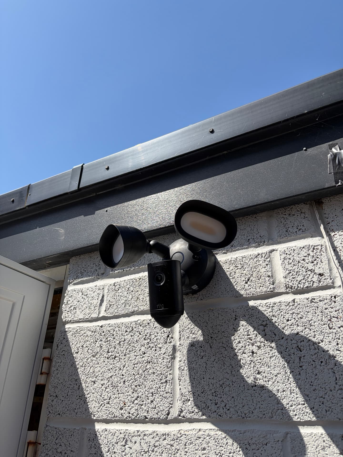 Ring floodlight camera fitted above a garage on a block wall
