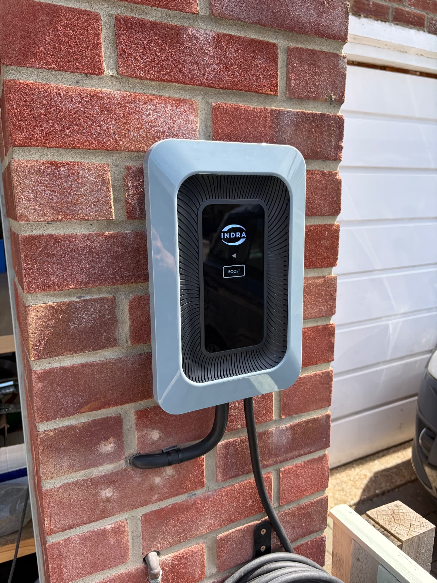 Indra EV charger installed on a brick wall next to a garage in Southampton